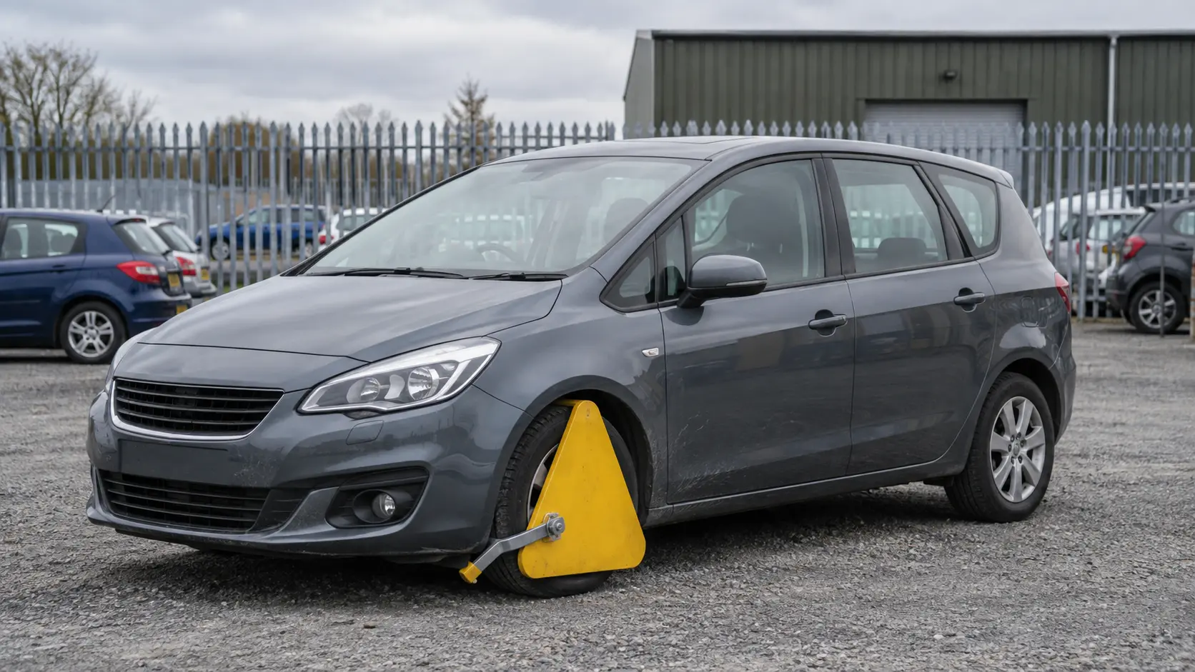 An ordinary car secured with a wheel clamp in a vehicle compound